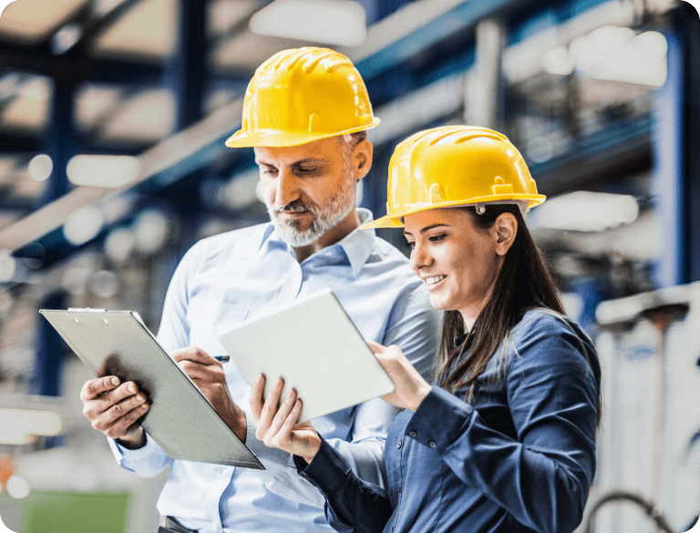Photo of a 2 people in construction hats comparing notes